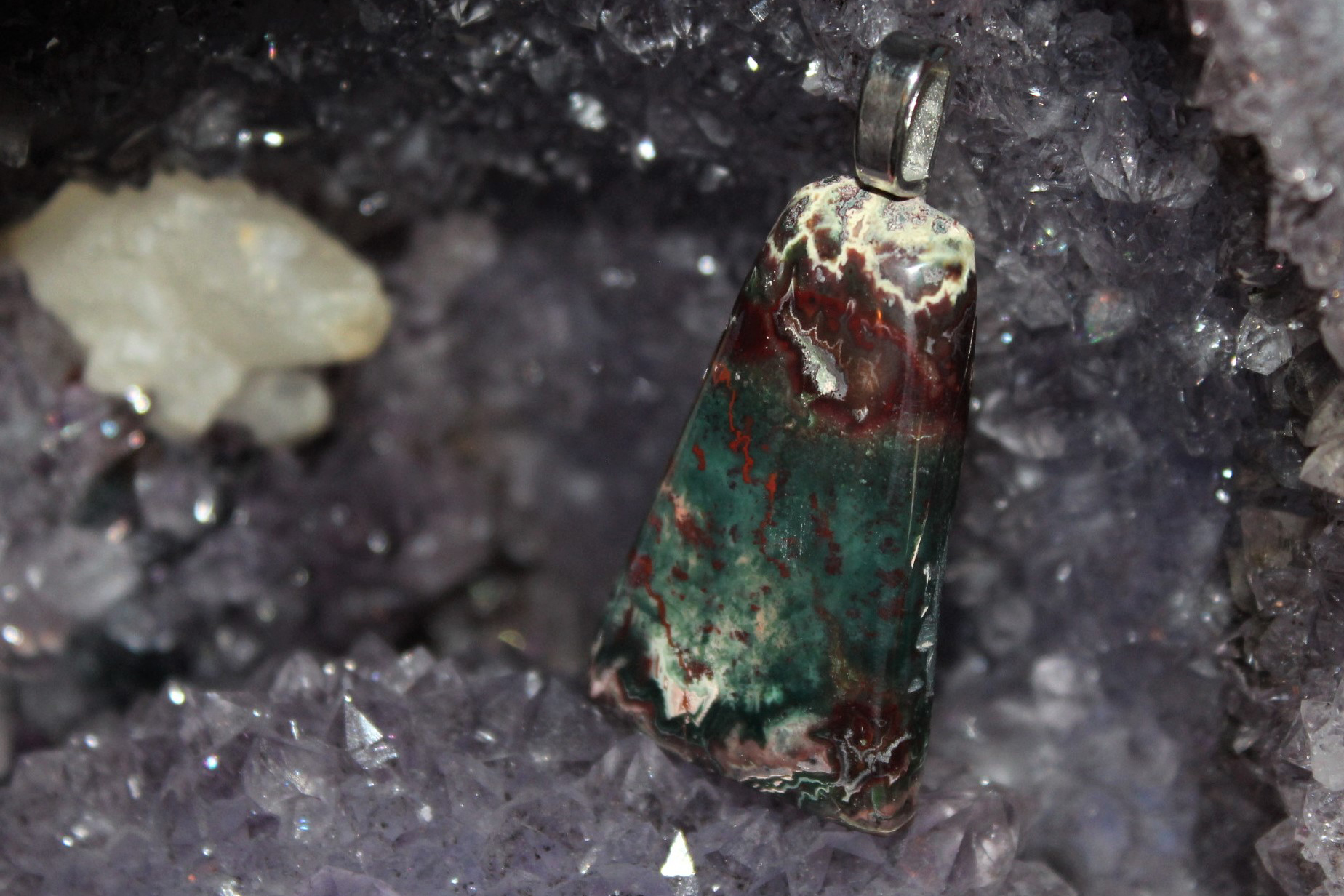 A trapezoidal pendant nestled into an amethyst geode